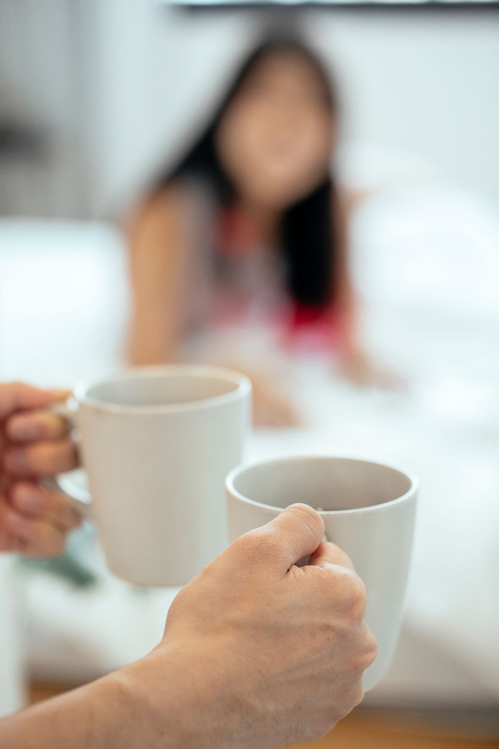 Hands sharing two cups of tea across a table